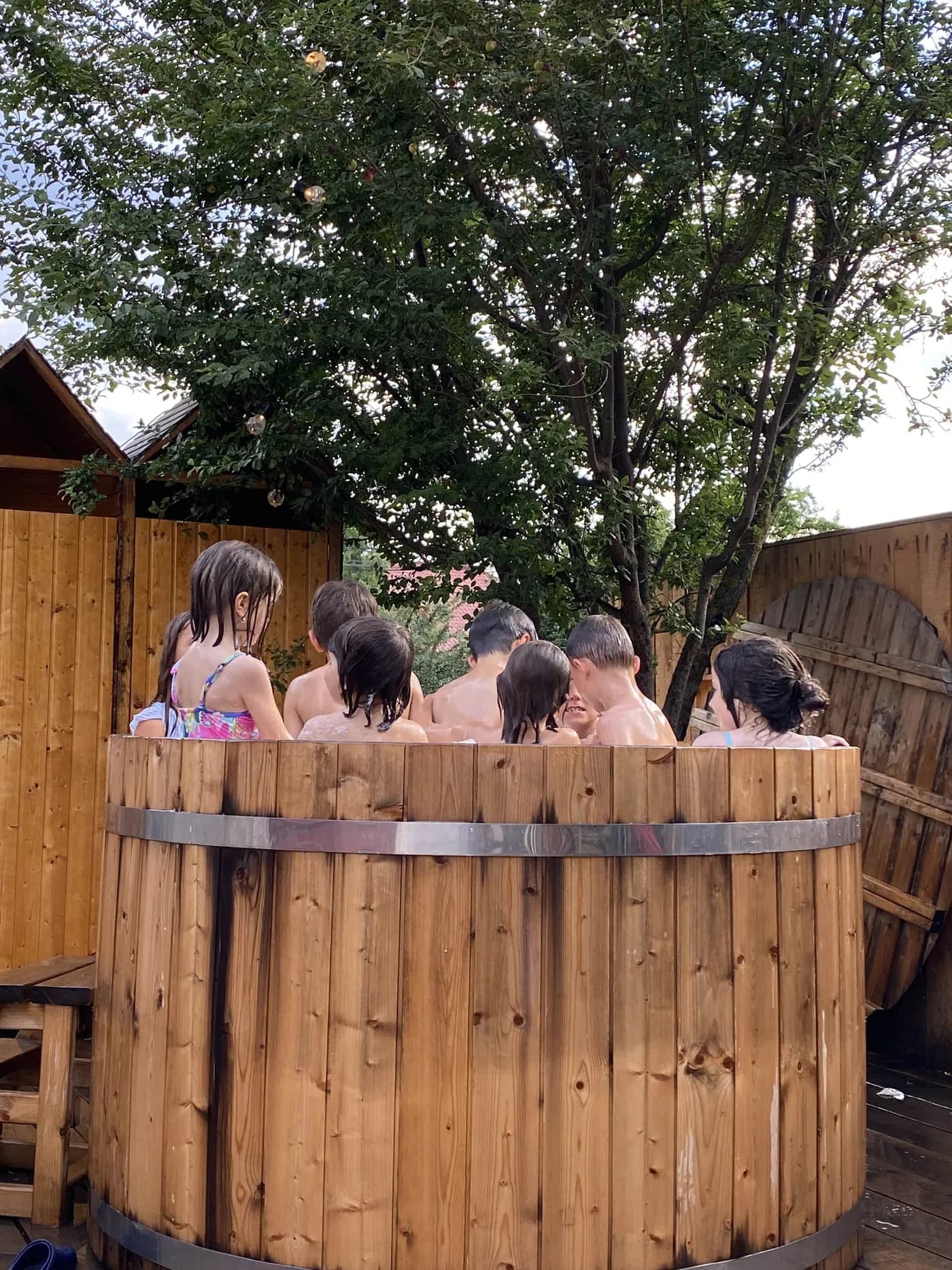 Un grup de copii se răcorește în ciubărul de lemn de pe terasă